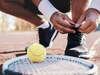 joueur de tennis refaisant son lacet